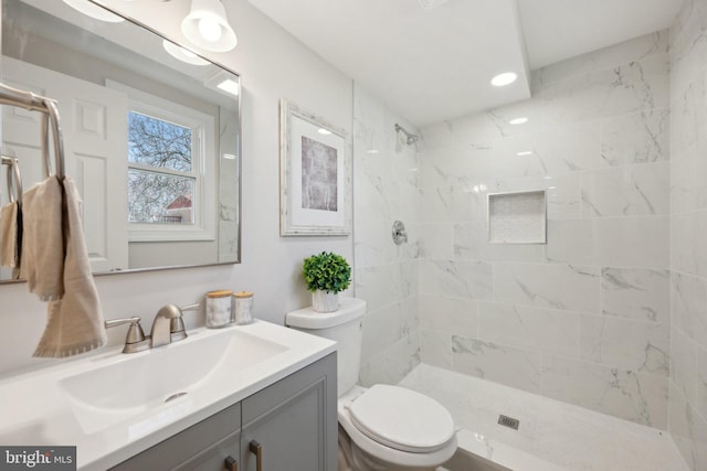 full bathroom with a tile shower, vanity, and toilet