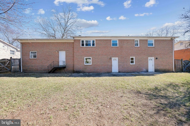 back of property with brick siding, a yard, and fence