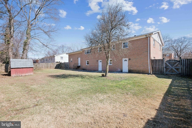 rear view of property featuring a fenced backyard, a storage shed, brick siding, a yard, and a gate