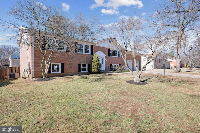 split foyer home with a garage, cooling unit, brick siding, and a front yard