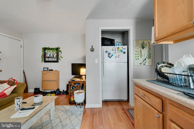 kitchen with white refrigerator, light hardwood / wood-style floors, and light brown cabinets