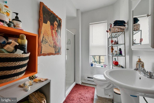 bathroom with sink, a shower with door, toilet, and baseboard heating