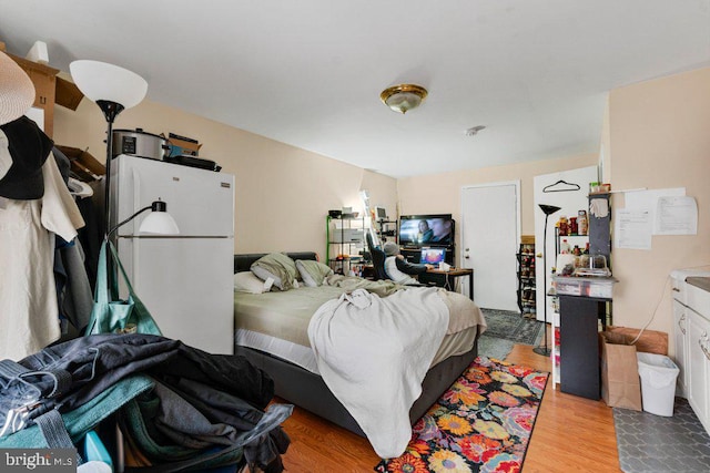 bedroom featuring light hardwood / wood-style flooring and white refrigerator