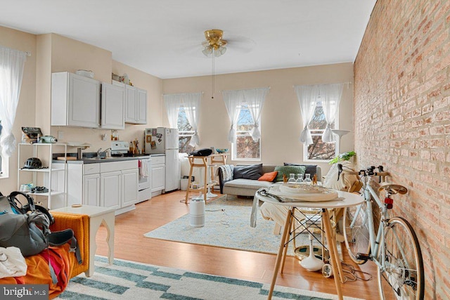 living room with ceiling fan, brick wall, and light wood-type flooring