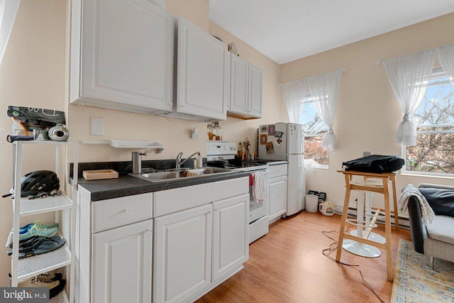 kitchen with white appliances, plenty of natural light, sink, and white cabinets