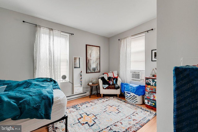 bedroom featuring hardwood / wood-style floors, baseboard heating, and cooling unit