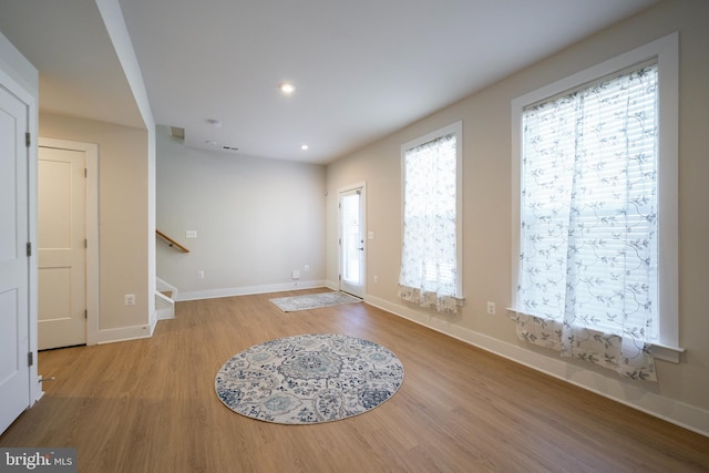 foyer featuring light wood finished floors, baseboards, stairway, and recessed lighting