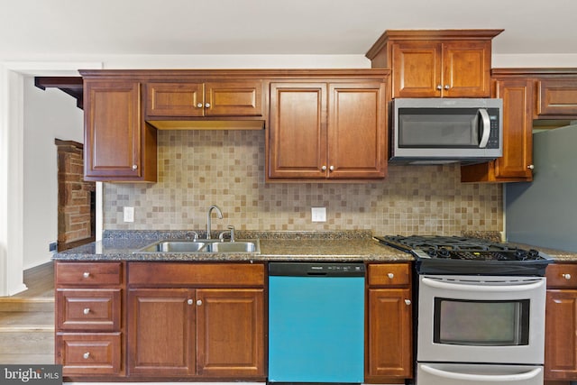 kitchen featuring dark stone countertops, decorative backsplash, stainless steel appliances, and a sink