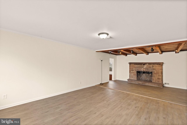 unfurnished living room with beam ceiling, a fireplace, visible vents, wood finished floors, and baseboards