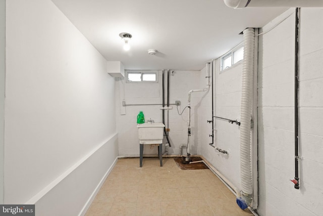 laundry room featuring a wealth of natural light, a sink, and concrete block wall