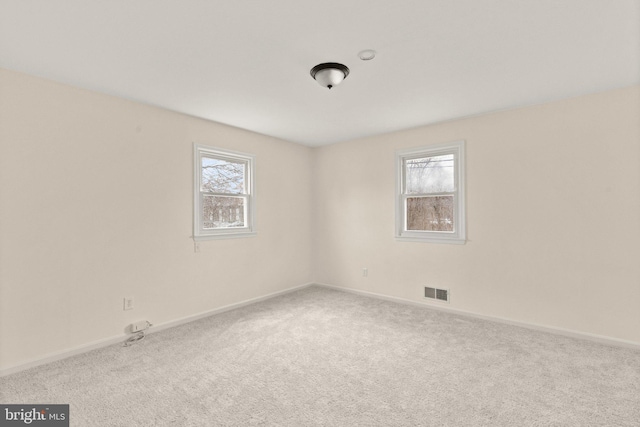 empty room featuring baseboards, plenty of natural light, visible vents, and carpet flooring