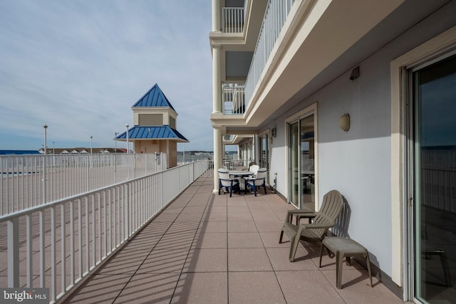 view of patio featuring a balcony and a water view