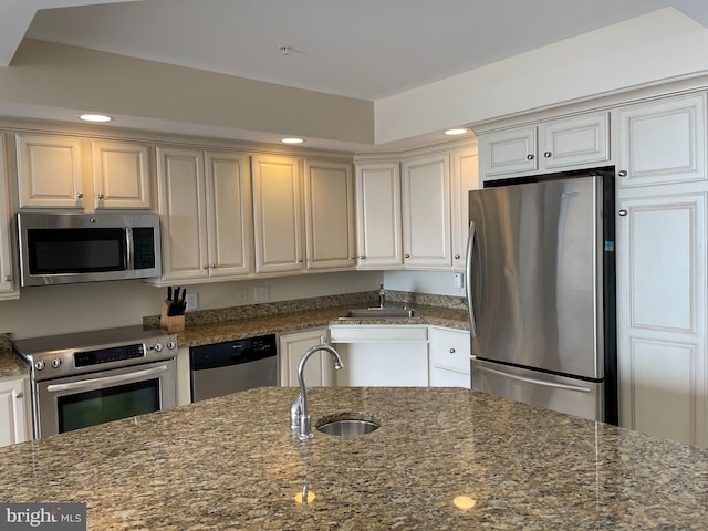 kitchen featuring stainless steel appliances, sink, and dark stone countertops