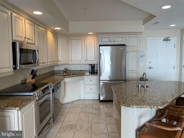 kitchen with sink, a kitchen bar, dark stone counters, a center island, and stainless steel appliances