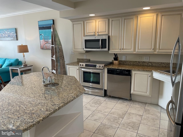 kitchen with sink, appliances with stainless steel finishes, light stone counters, cream cabinets, and ornamental molding