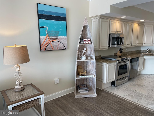 kitchen featuring appliances with stainless steel finishes, sink, light wood-type flooring, and dark stone counters