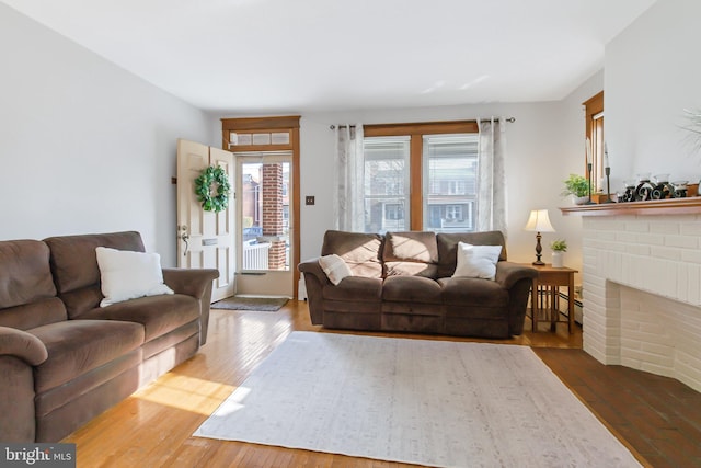 living room featuring baseboard heating, a fireplace, hardwood / wood-style floors, and a wealth of natural light