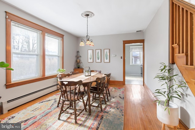 dining area with hardwood / wood-style flooring, a chandelier, and baseboard heating