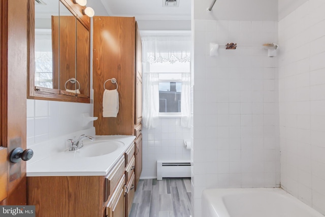 bathroom featuring vanity, a baseboard radiator, tile walls, and plenty of natural light