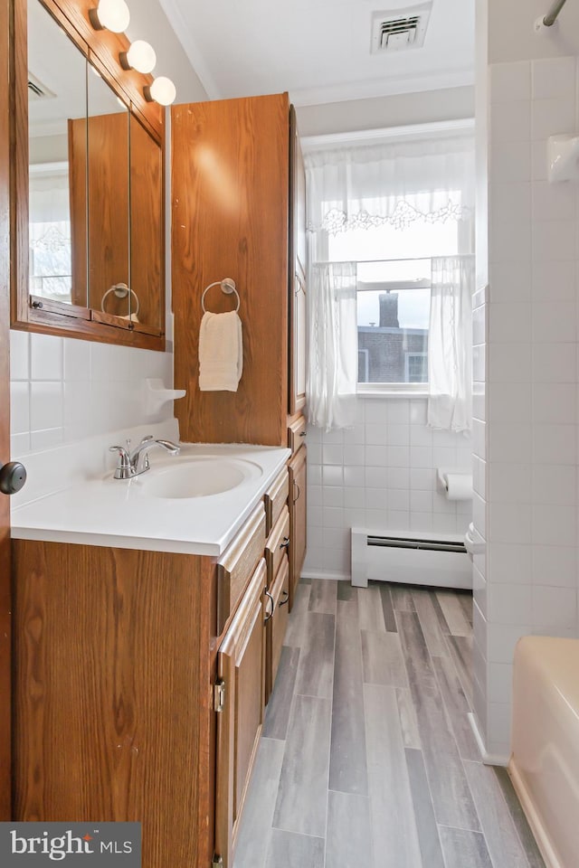 bathroom with hardwood / wood-style flooring, a baseboard radiator, tile walls, and vanity