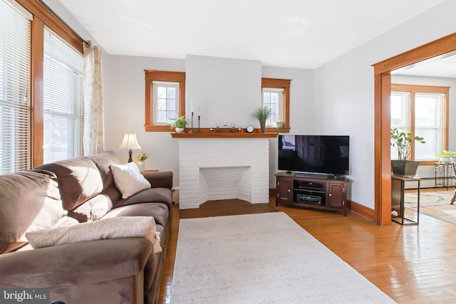 living room with hardwood / wood-style floors, a brick fireplace, and a baseboard heating unit