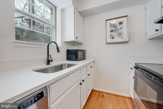 kitchen with sink, light hardwood / wood-style flooring, stainless steel appliances, extractor fan, and white cabinets