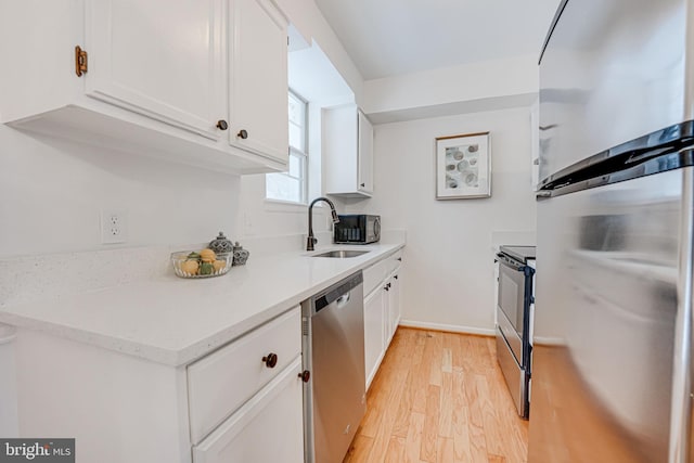 kitchen featuring white cabinetry, appliances with stainless steel finishes, sink, and light hardwood / wood-style flooring