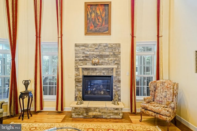 sitting room with a stone fireplace, wood finished floors, and baseboards