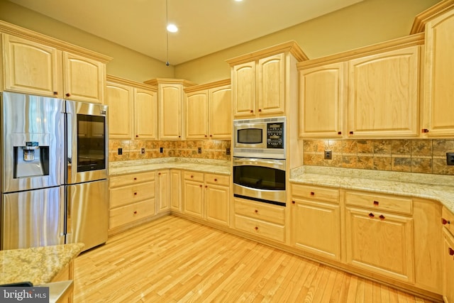 kitchen with appliances with stainless steel finishes, light wood-type flooring, light brown cabinets, and decorative backsplash