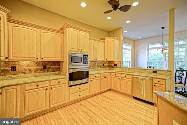 kitchen with tasteful backsplash, appliances with stainless steel finishes, a sink, and light brown cabinetry