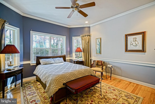 bedroom with ornamental molding, multiple windows, wood finished floors, and baseboards