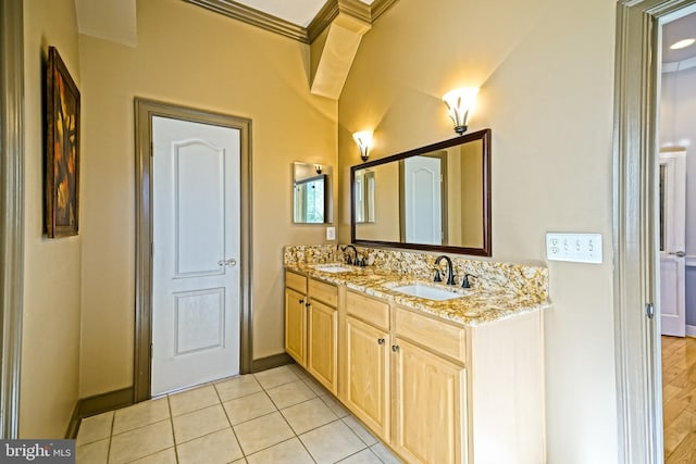 bathroom featuring tile patterned flooring, a sink, baseboards, and double vanity