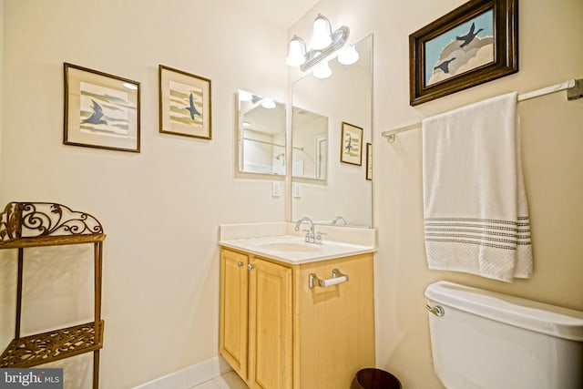 bathroom with tile patterned flooring, baseboards, vanity, and toilet