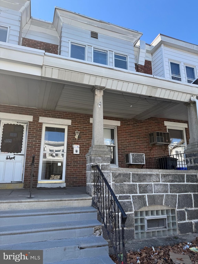 entrance to property featuring a wall unit AC and a porch