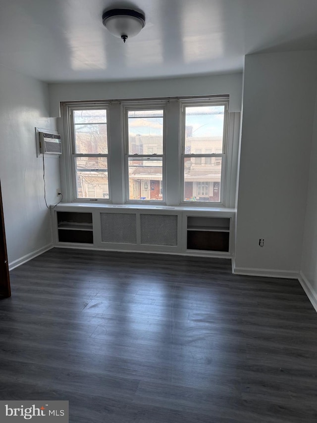 unfurnished room with radiator heating unit, dark hardwood / wood-style floors, and a wall mounted air conditioner