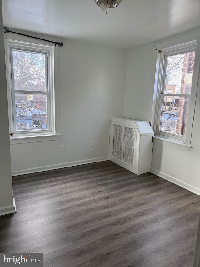 empty room with a wealth of natural light and dark hardwood / wood-style floors