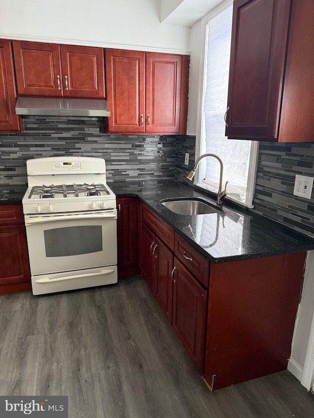 kitchen with sink, white range with gas stovetop, tasteful backsplash, dark hardwood / wood-style floors, and dark stone counters