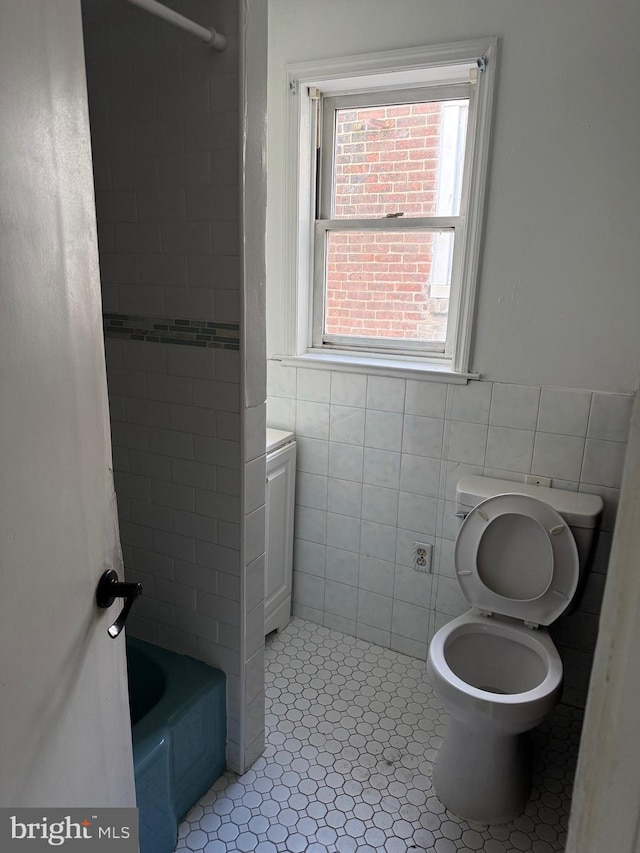 bathroom featuring toilet and tile walls