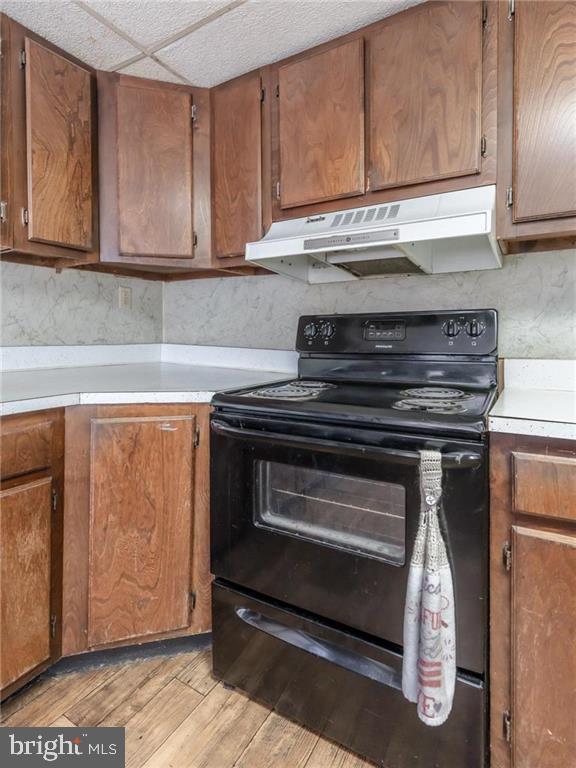 kitchen featuring a drop ceiling, black range with electric stovetop, and light hardwood / wood-style floors