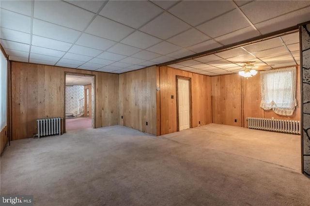 basement featuring carpet flooring, radiator heating unit, and wooden walls