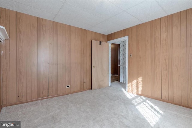 carpeted spare room with wood walls