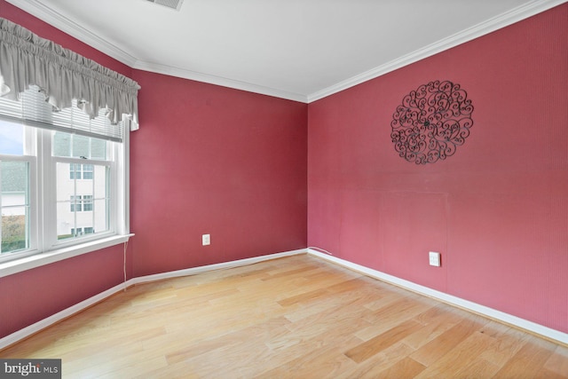 empty room featuring baseboards, ornamental molding, and wood finished floors