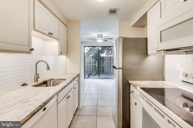 kitchen featuring white appliances, light stone counters, light tile patterned floors, sink, and white cabinetry