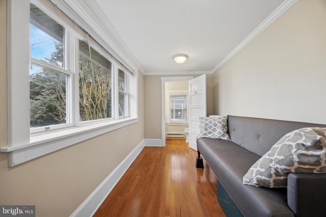 living area with crown molding, a baseboard radiator, and hardwood / wood-style floors