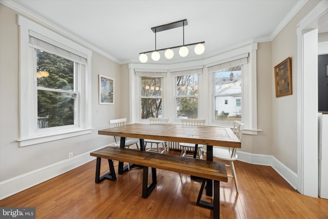 dining space with wood-type flooring, ornamental molding, and a healthy amount of sunlight