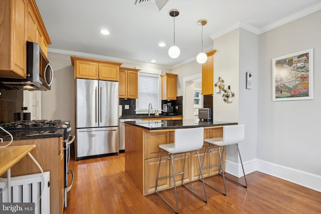 kitchen with sink, a breakfast bar area, hanging light fixtures, stainless steel appliances, and kitchen peninsula