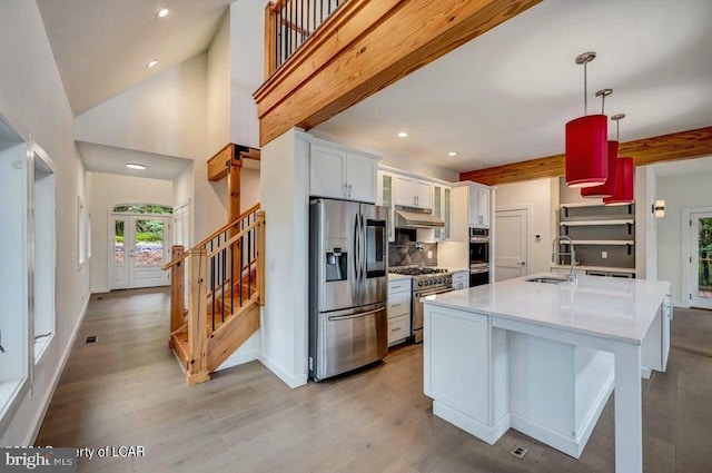 kitchen featuring sink, white cabinetry, pendant lighting, stainless steel appliances, and light hardwood / wood-style floors