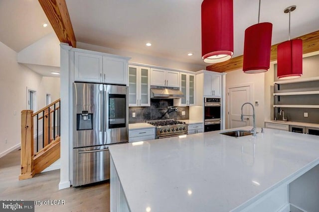 kitchen with sink, white cabinetry, hanging light fixtures, appliances with stainless steel finishes, and decorative backsplash