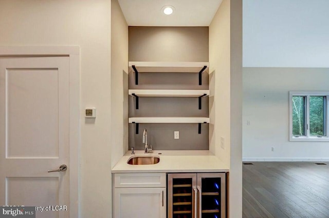 bar featuring wine cooler, dark hardwood / wood-style flooring, sink, and white cabinets