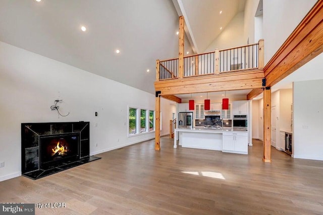 unfurnished living room with high vaulted ceiling, a high end fireplace, and light hardwood / wood-style floors